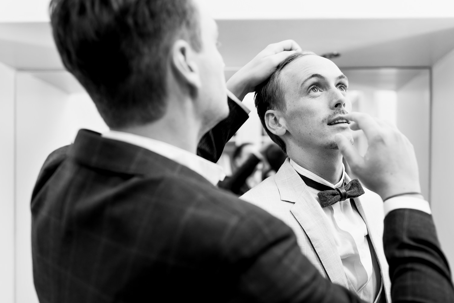 The groom looks up to the skylight as his brother styles his hair using his hands at Double Vision house before a St Francis Links wedding