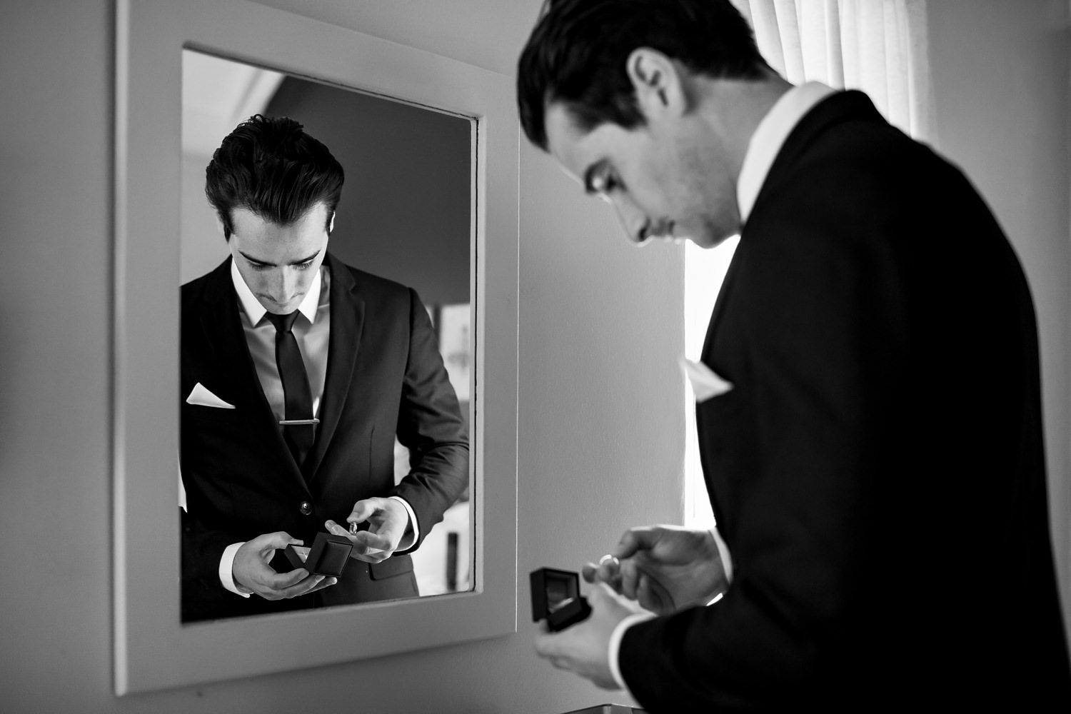 The groom with white pocket square is reflected in a mirror as he does final checks on the wedding rings at The Plantation, a symbol of dedication and a celebration of love