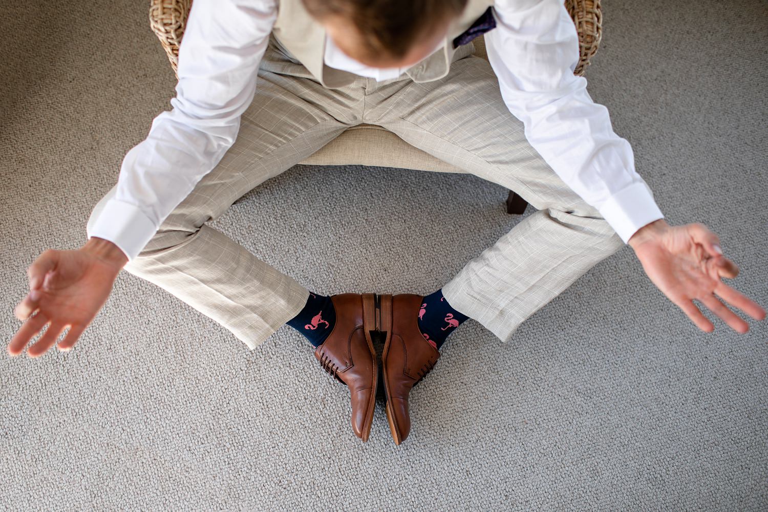 The groom takes a minute to strike a meditation pose, exposing his flamingo socks before he travels to greet guests at the wedding ceremony. Photography by wedding photographer in South Africa.
