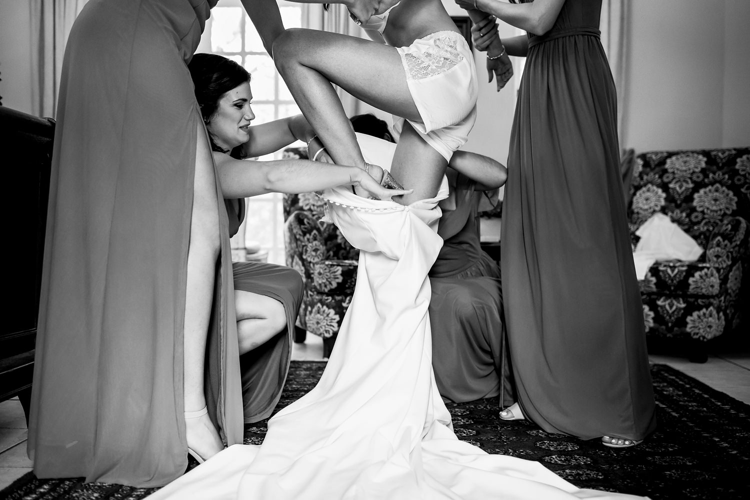 Bridesmaids help a bride step in to her wedding gown at The Plantation Wedding Venue