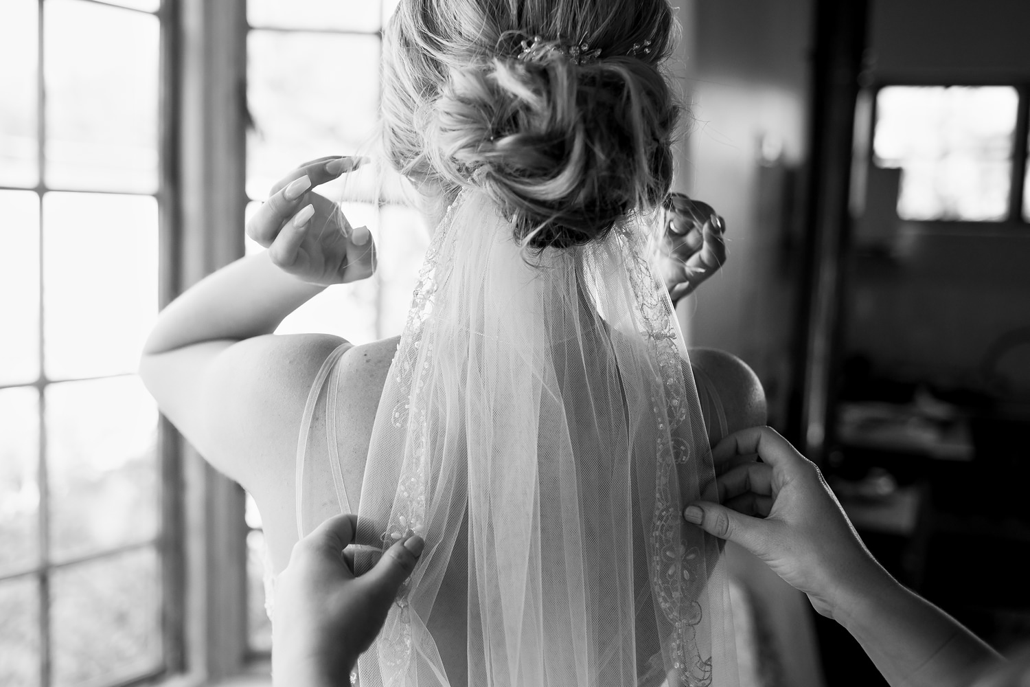 Finishing touches to the veil placement under a messy bun