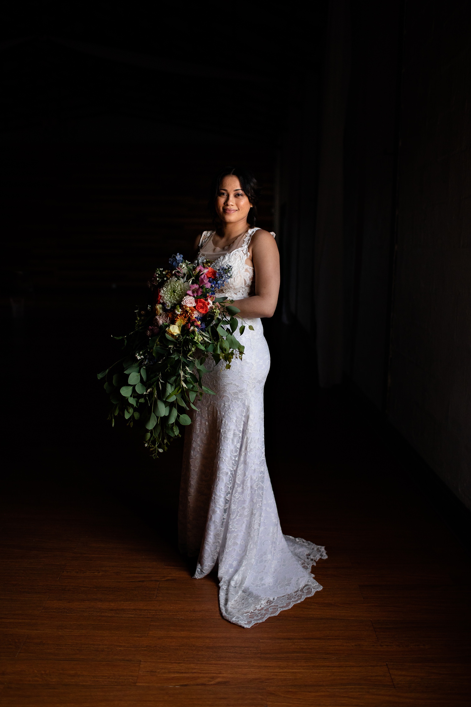 Classic portrait of a bride standing in a patch of light with her cascading bouquet by Niki M, Johannesburg Wedding Photographer