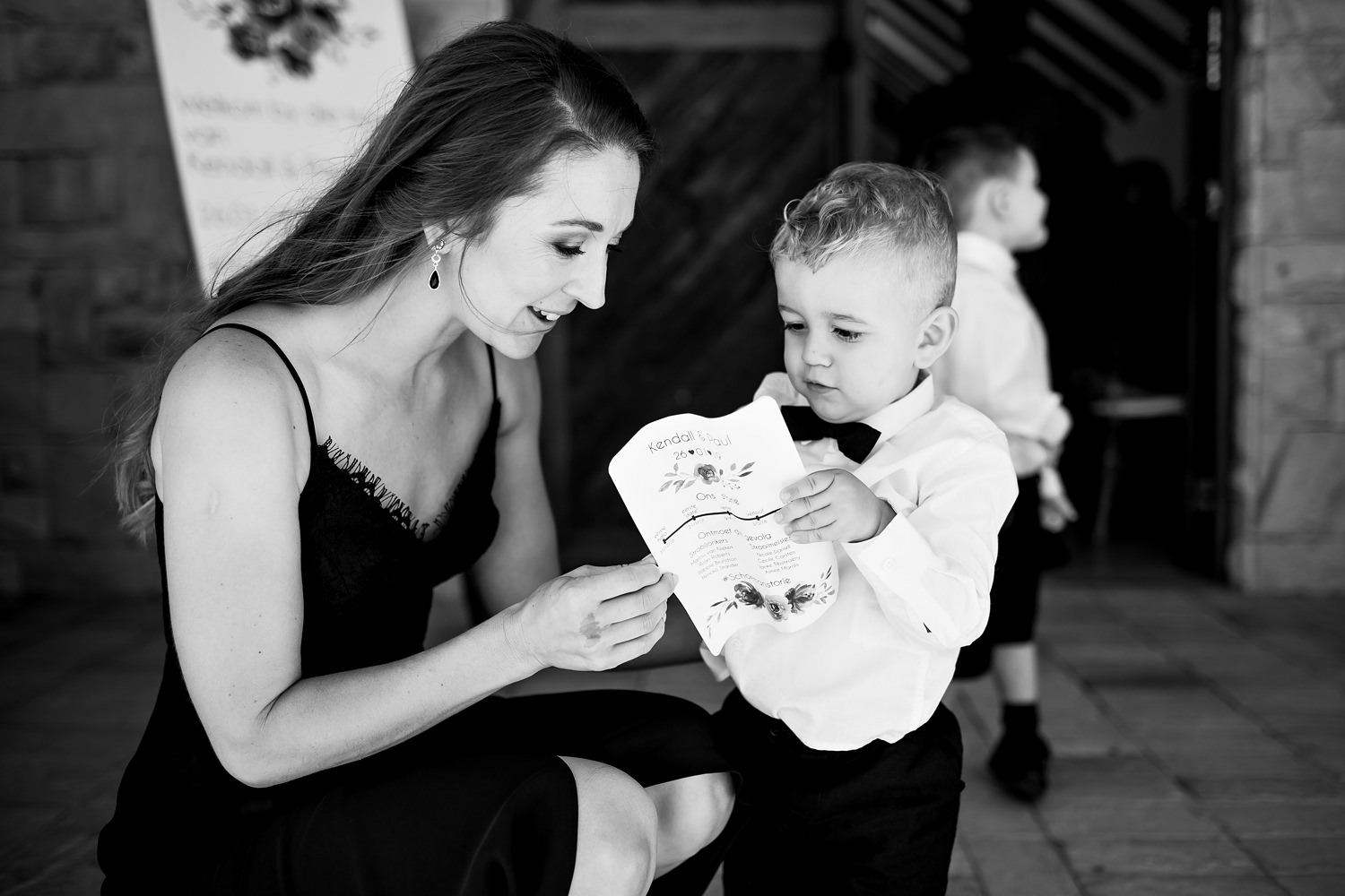 The bowtied ringbearer and his mother study a wedding programme outside the arched chapel entrance at Blomfontein Wedding Venue