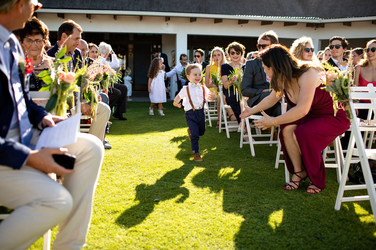 The ringbearer runs down the grass aisle to his mother at a St Francis Links ceremony
