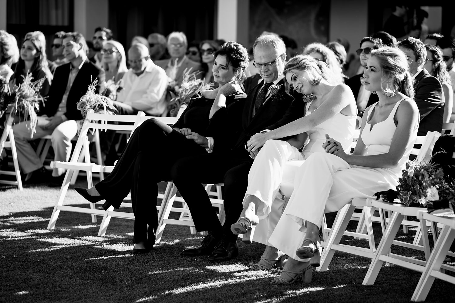 The bride's family embrace during a ceremony prayer. Classic black and white documentary photograph by by wedding photographer in South Africa, Niki M Photography