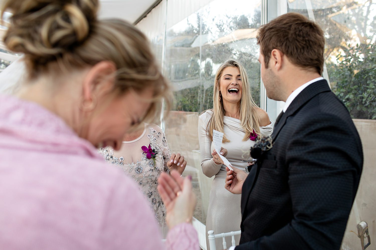 The mother of the groom laughs at her son as he entrusts her with the safekeeping of the wedding certificate by wedding photographer in South Africa, Niki M Photography