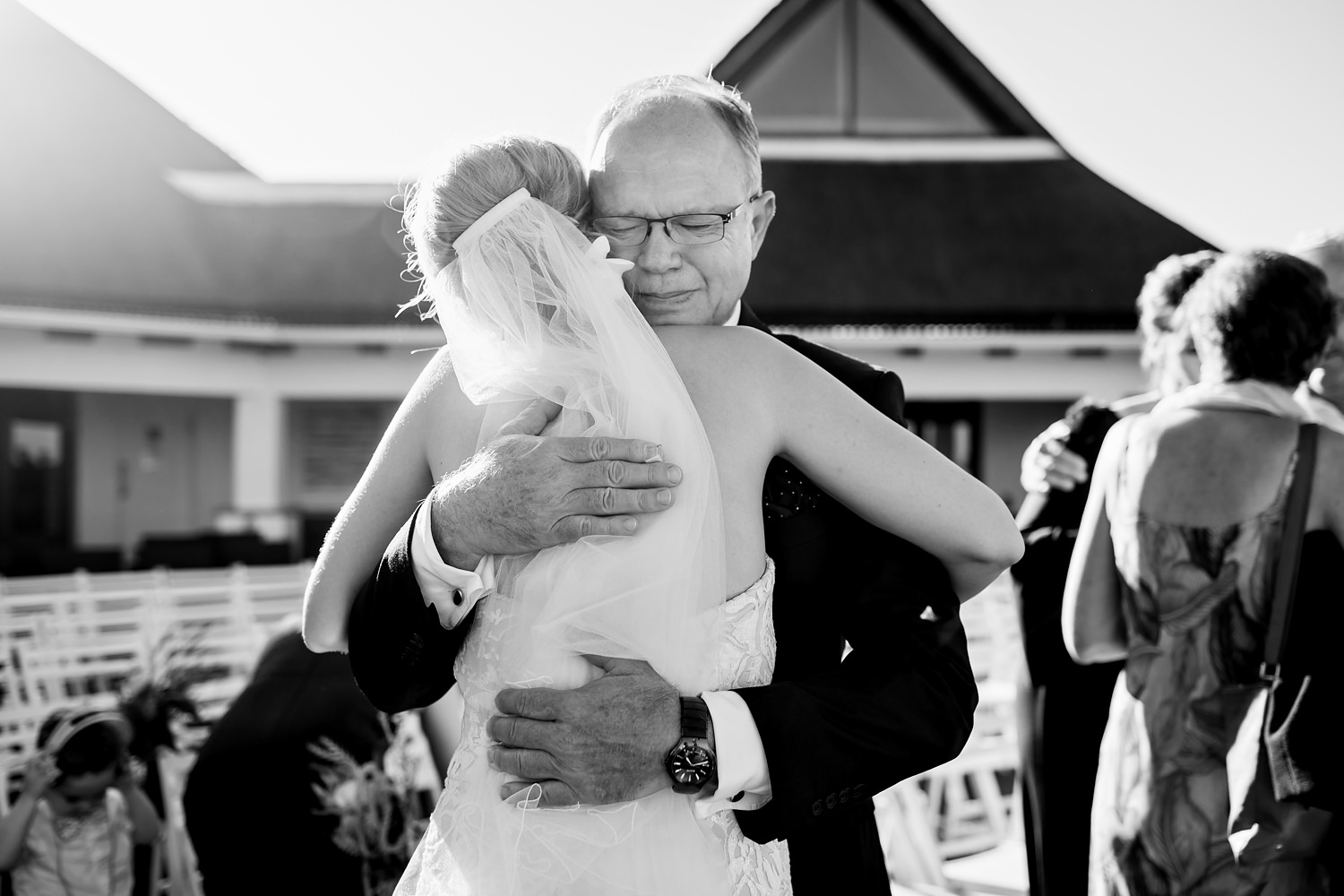Image of the father of the bride crying as he hugs his daughter post-ceremony by wedding photographer in South Africa, Niki M Photography