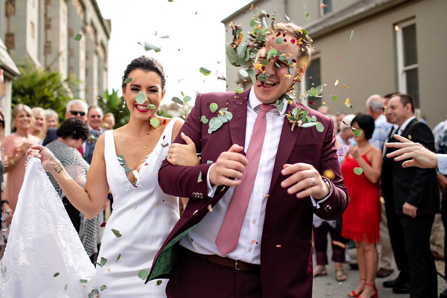 The groom gets a face full of pennygum confetti and rose petals at their wedding in South Africa by photographer Niki M