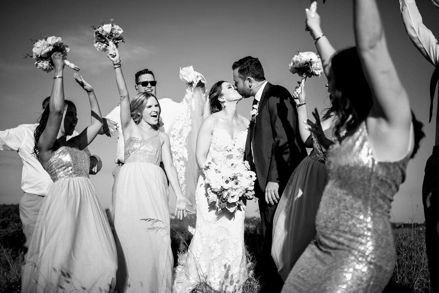 A photograph of the bridal entourage cheering as the bride and groom kiss by wedding photographer in South Africa, Niki M Photography
