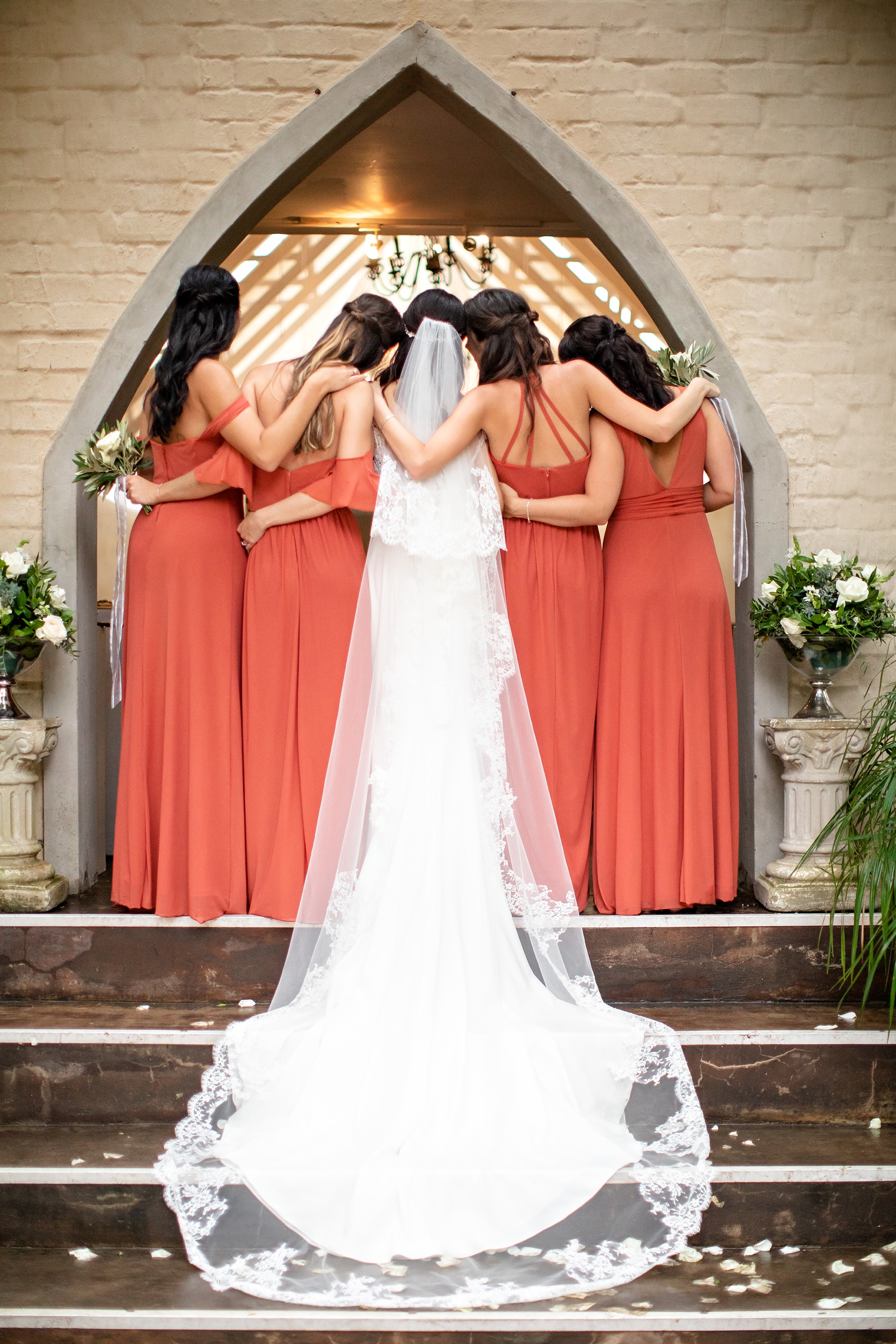 Styled bridesmaid photo from behind the group as they embrace the bride