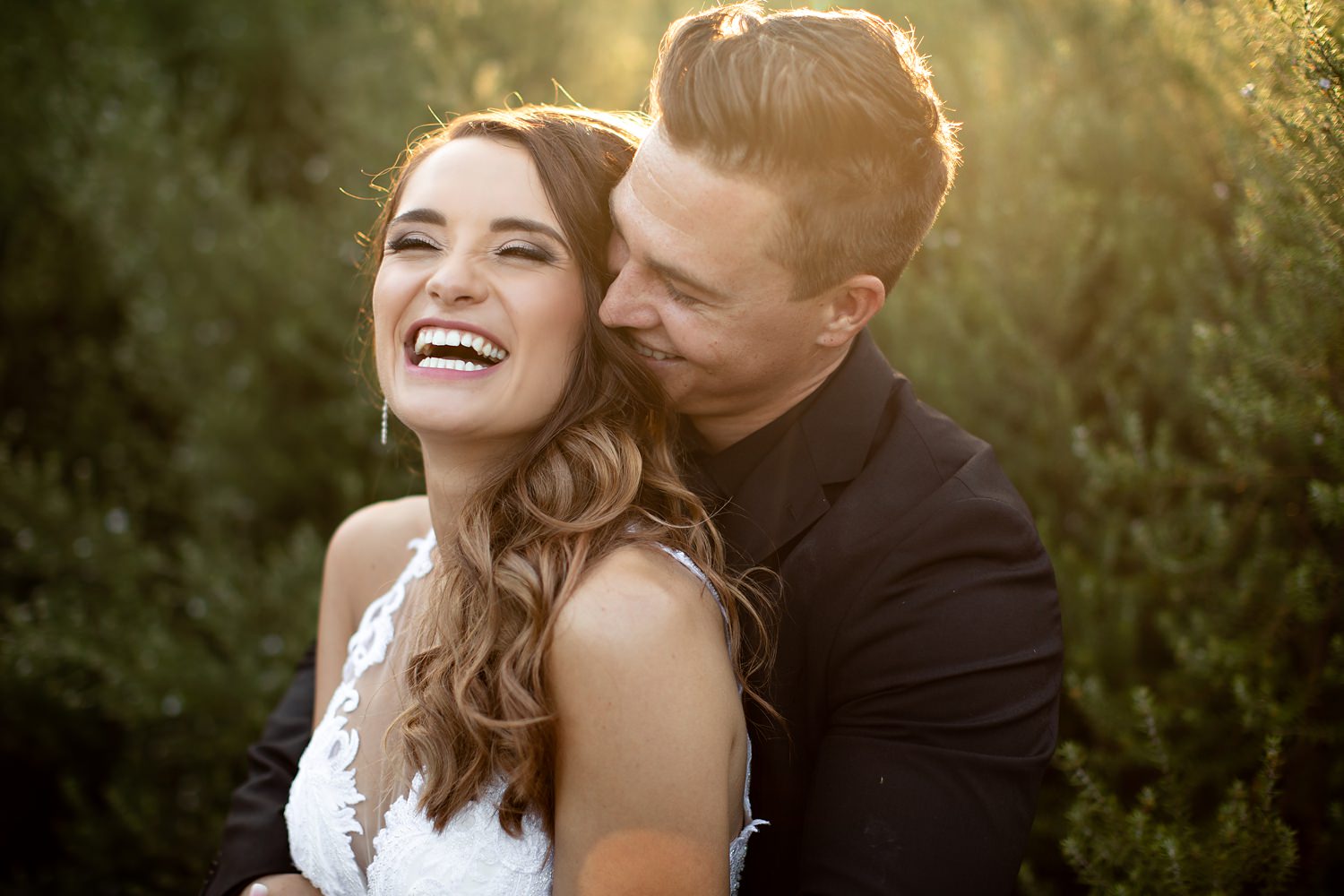 Backlit bride and groom laugh during their creative photography session at The Rose Barn by wedding photographer in South Africa, Niki M Photography