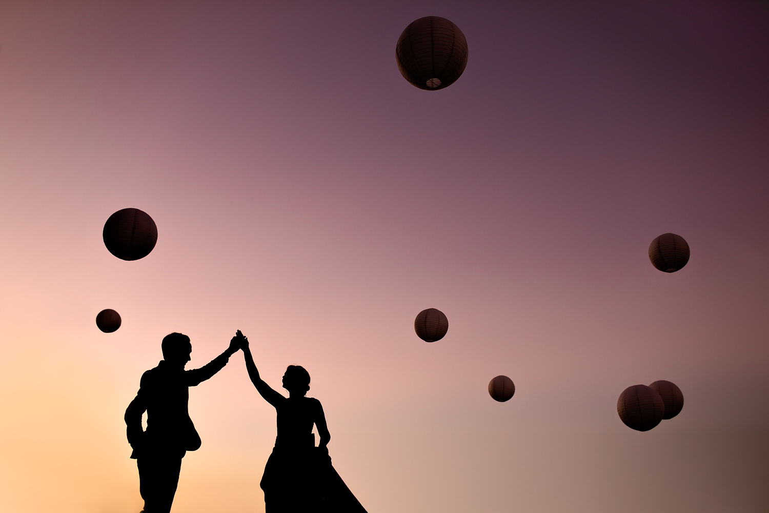 Creative silhouette photograph of the bride and groom dancing under paper lanterns at sunset and celebrating their love and wedding day by wedding photographer in South Africa, Niki M Photography