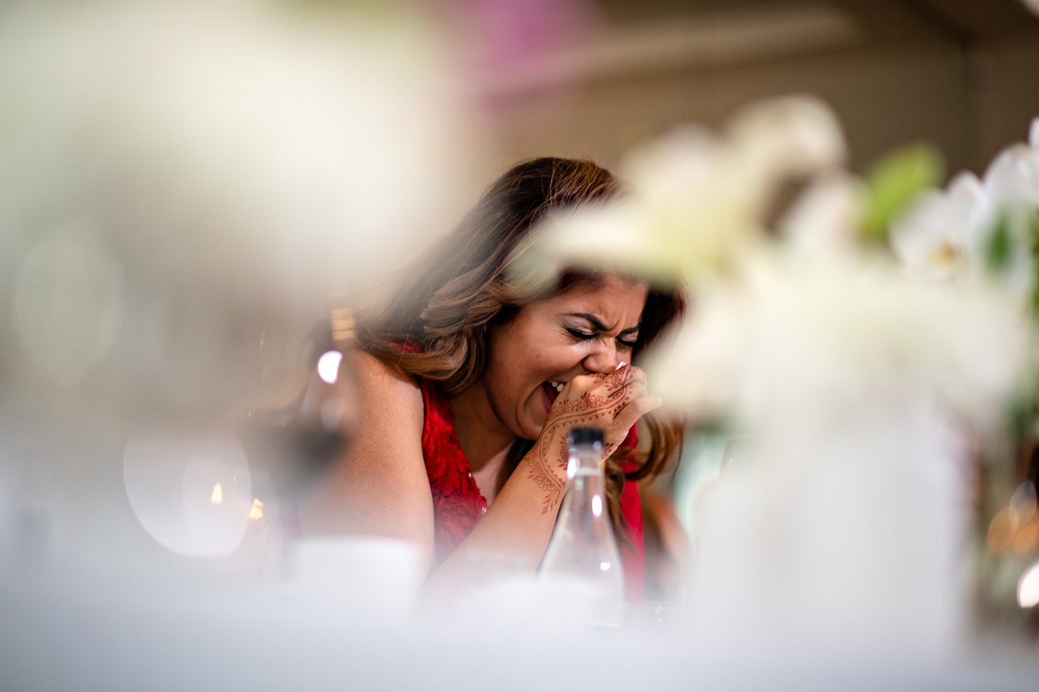 The bride laughs hysterically during speeches at her wedding