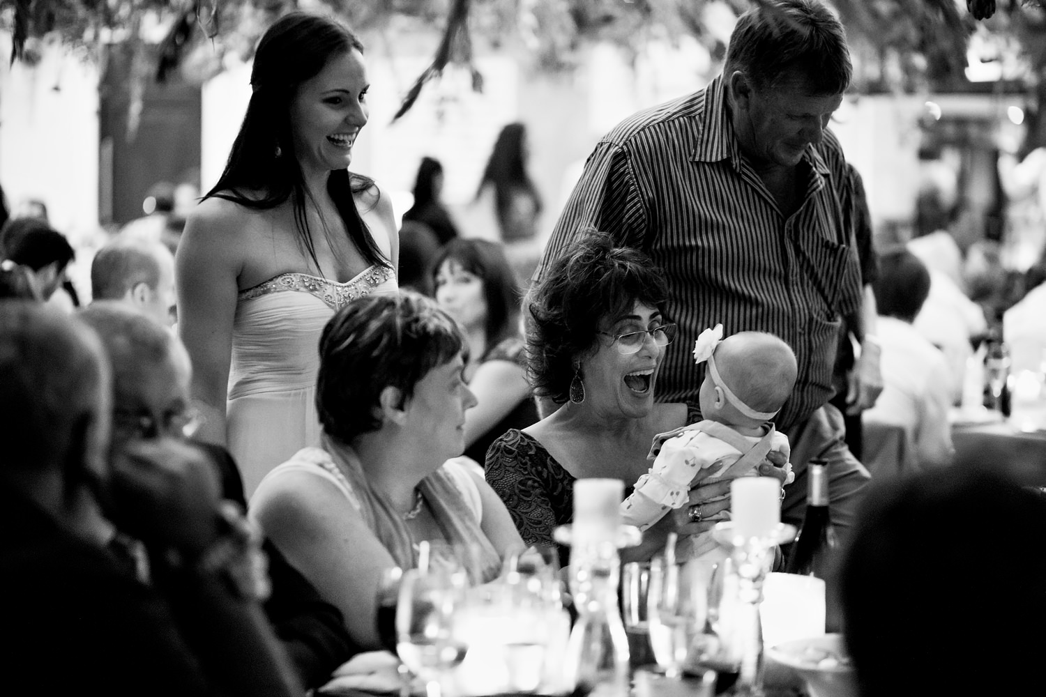 A woman plays peekaboo with a baby during a wedding reception