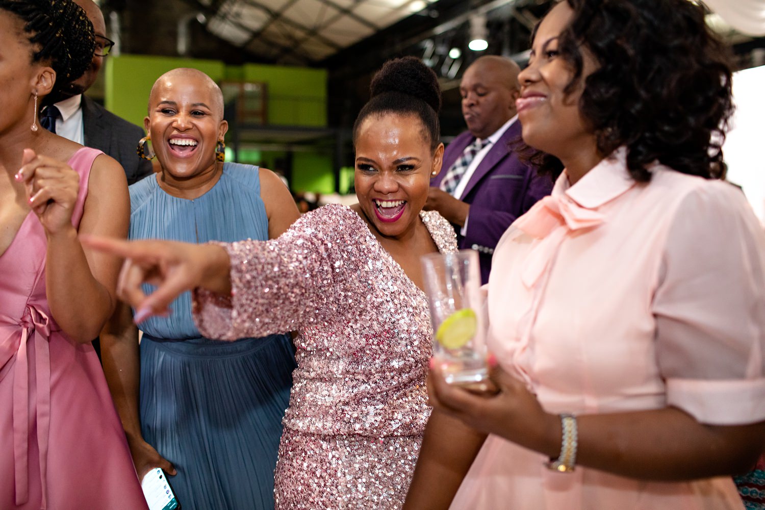 A woman in a pink sequin top dances and points in this fun wedding dancefloor moment by wedding photographer in South Africa, Niki M Photography