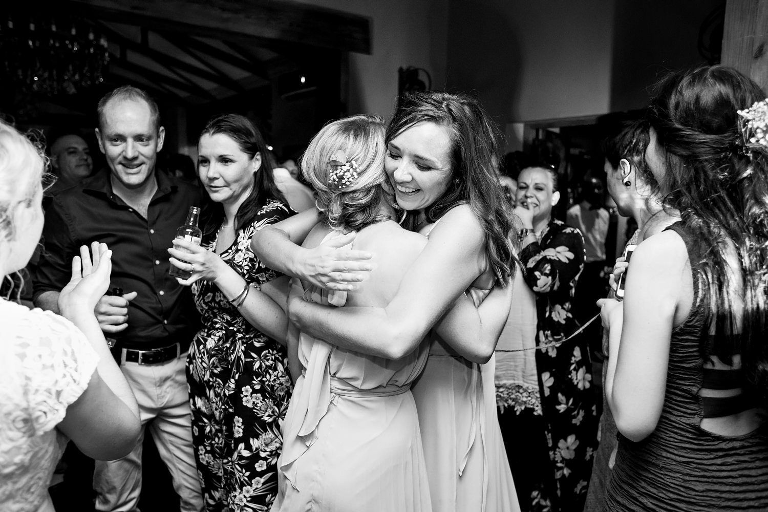 The bride and her bridesmaid hug in the middle of the dancefloor