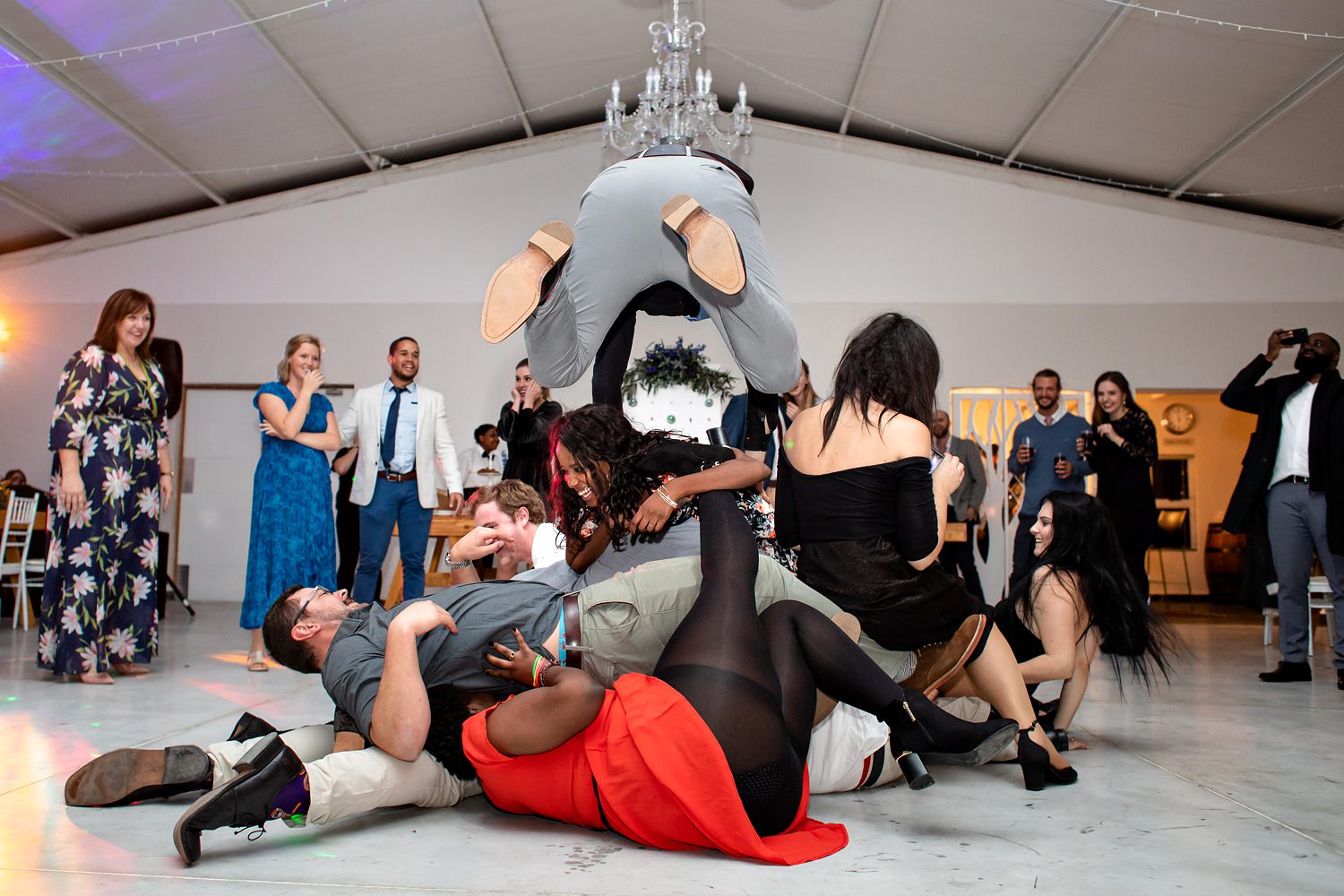 Guests pile up in the middle of the dancefloor during the song 'Free Fallin' by Tom Petty at the wedding reception, with one wedding guest in mid flight