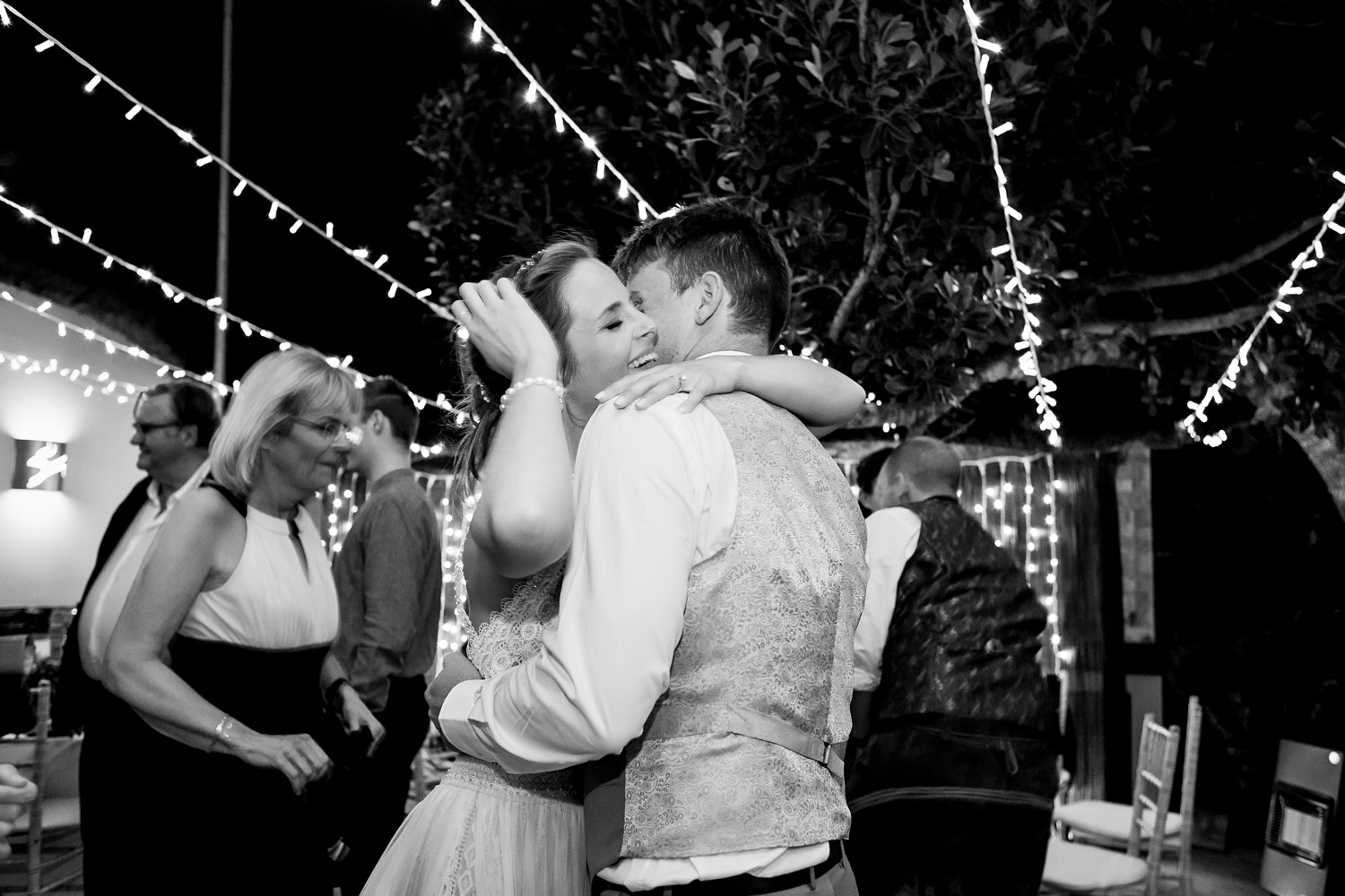 The bride hugs the groom and laughs on the dancefloor
