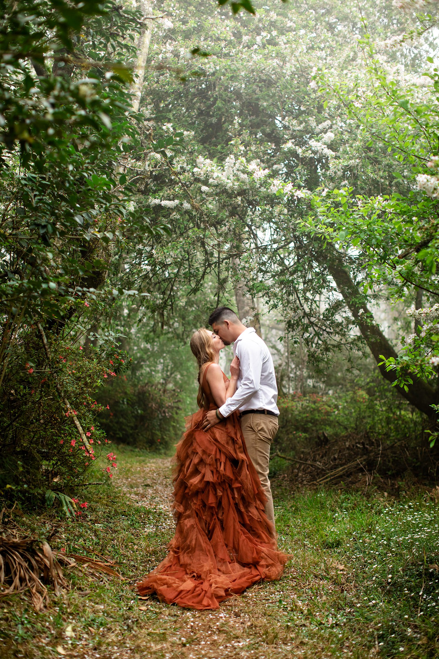 Bride and Groom stand on a winding path in Magoebaskloof with a cherry blossom canopy above them.
