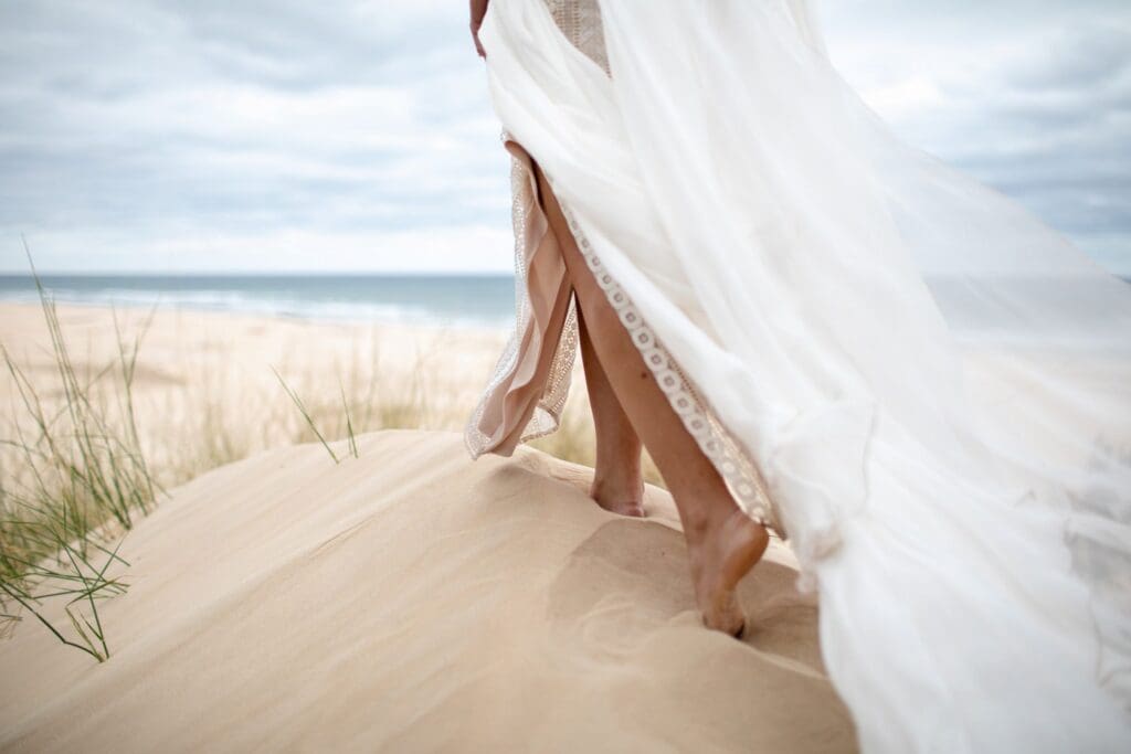 A bride walks on the soft sand dunes at Oceana Reserve in the Eastern Cape, a featured unique South African wedding venue in this article.