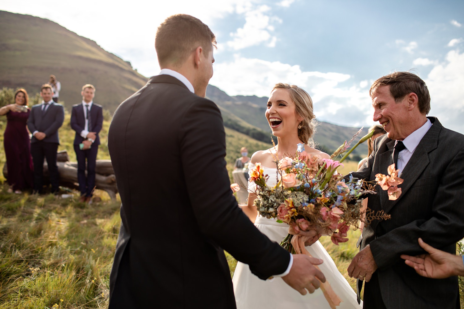 A bride laughs with delight as she sees the groom at their mountain top Southern Drakensberg wedding ceremony.