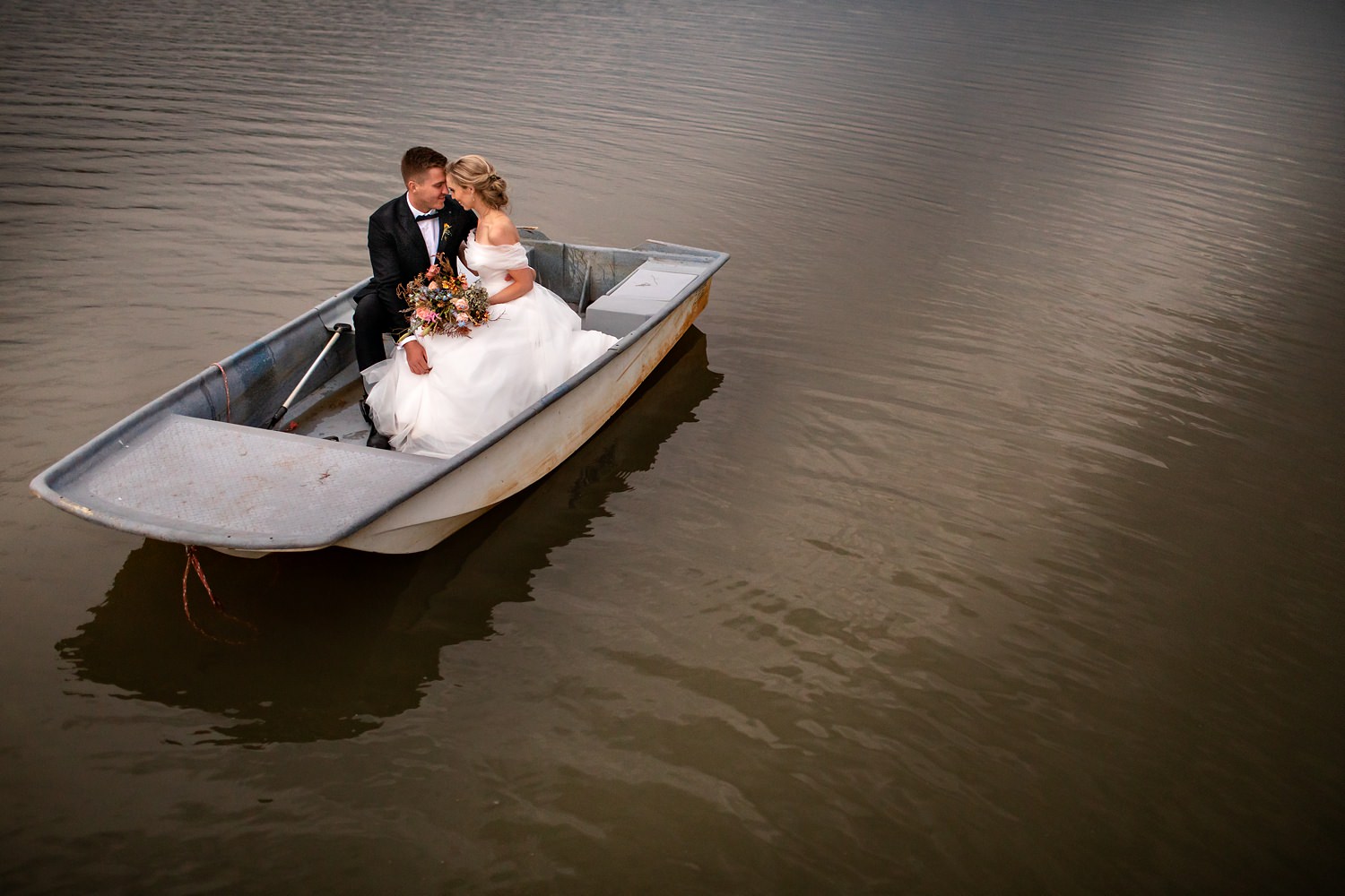 A bridal couple on a boat at St Bernards Lake after their Drakensberg wedding