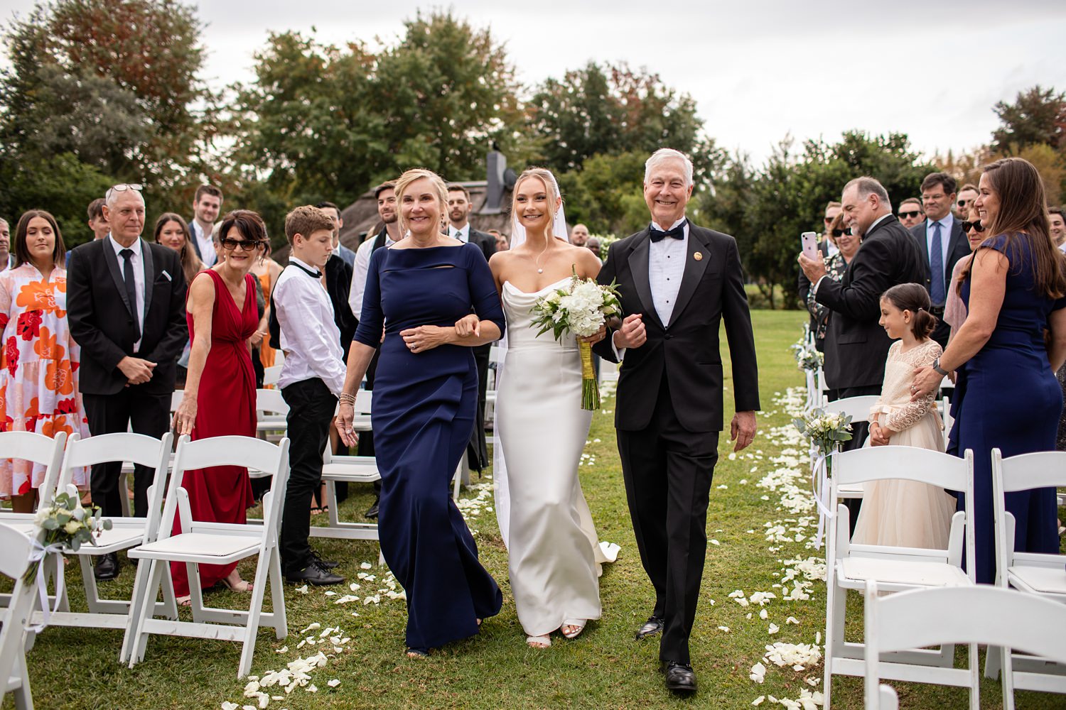 A bride walks dow the aisle with both parents at her Central Drakensberg Wedding