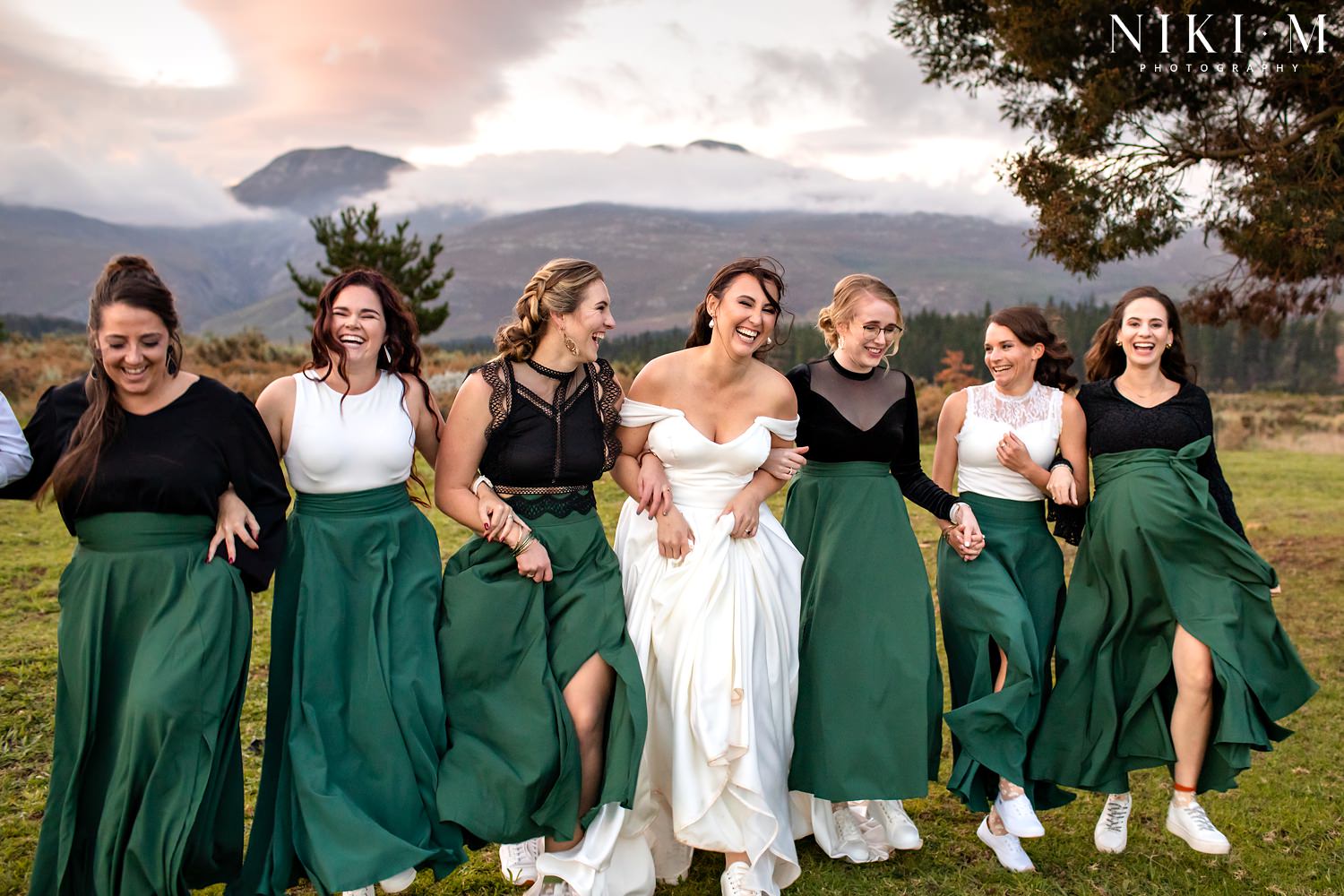 The bride walks with her bridesmaids as the sun sets behind them at an Elgin wedding.