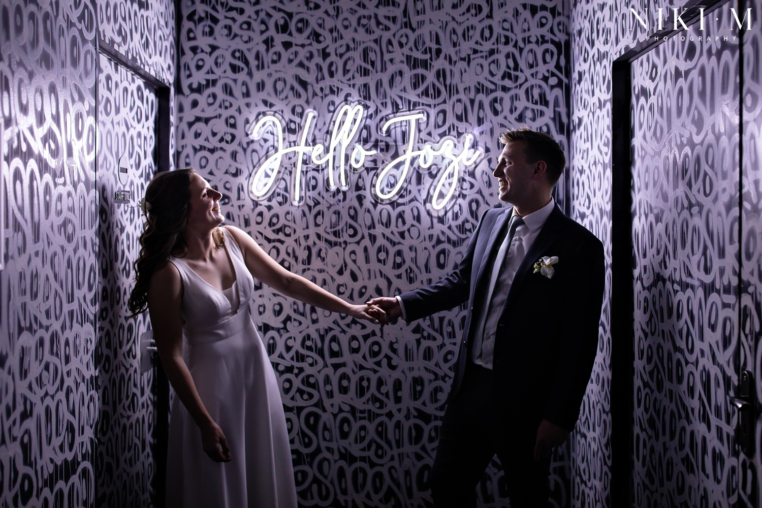 A couple in front of Hallmark House's Hello Jozi neon sign at their Johannesburg wedding