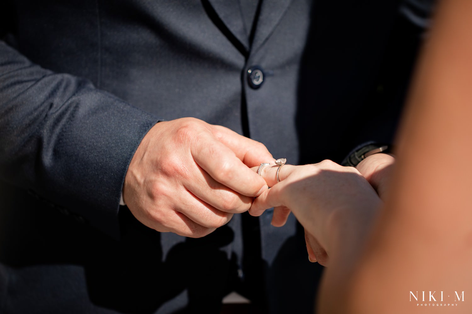 Bride and groom putting on wedding rings at their Cavalli Estate wedding in the sunken garden