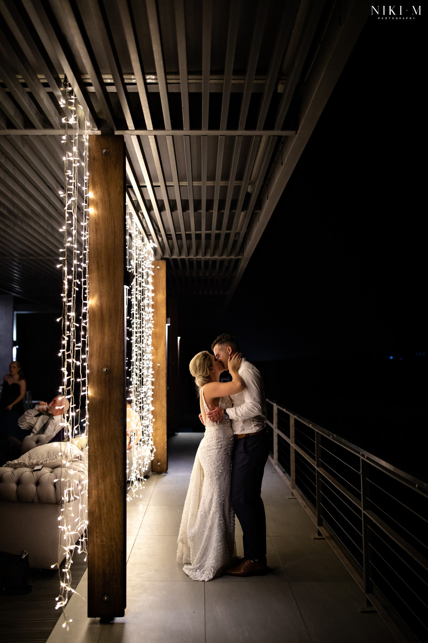 The bride and groom are photographed through the fairy lights at the end of the evening after their Cavalli estate wedding in the cape town winelands