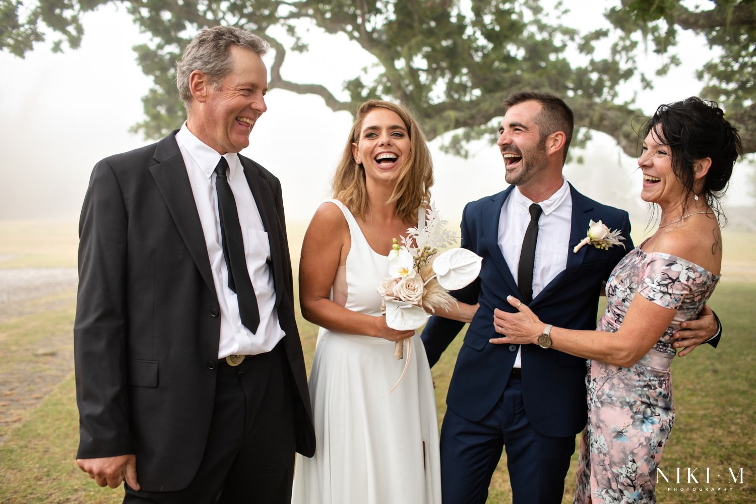 The bridal couple laugh with their parents at their misty wedding in The Crags, South Africa