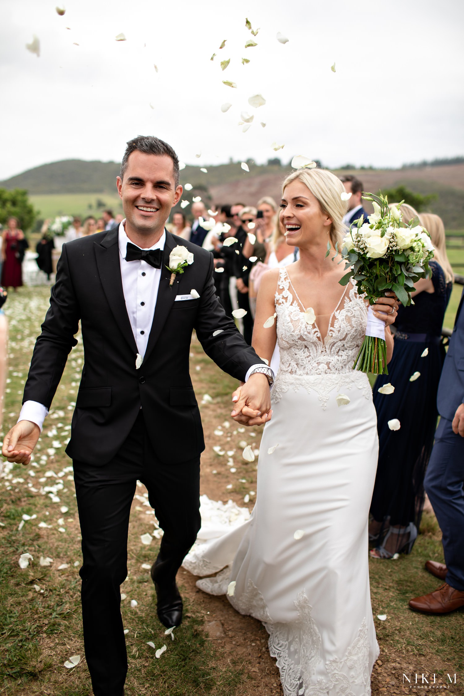 Bride and groom are showered with white petals at their garden route wedding in The Crags