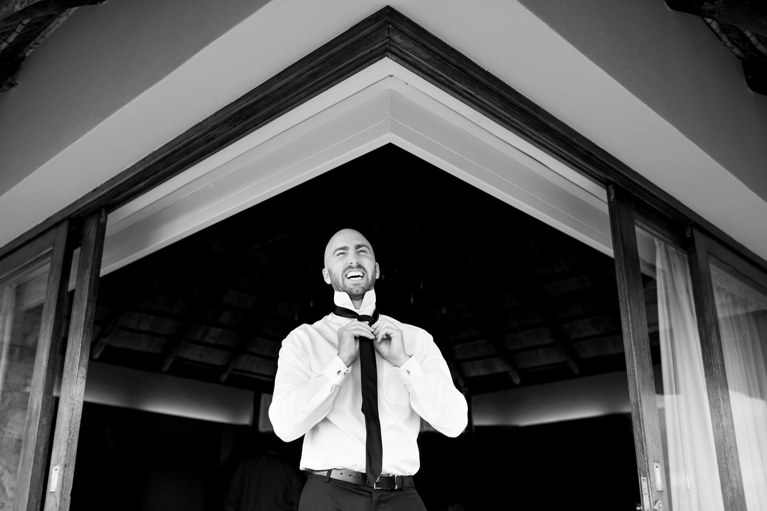 A groom gets ready for his South African destination safari wedding. Black and white image by safari photographer Niki M