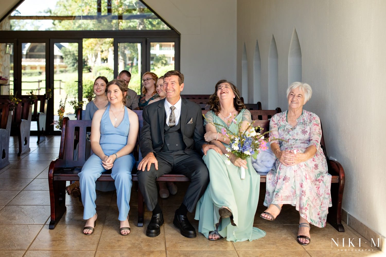 Family members seated in the chapel share laughter and smiles during the relaxed, joy-filled Champagne Castle Hotel micro-wedding ceremony.