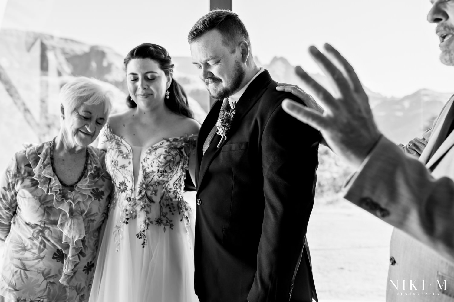 The bride and groom bow their heads in prayer with family during an emotional blessing inside the mountain-view chapel.