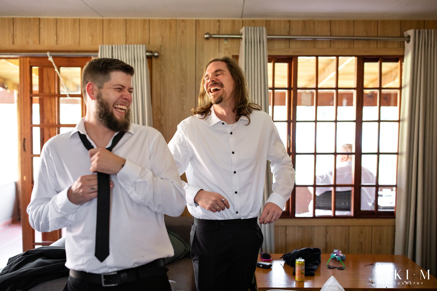 Groomsmen laughing together while getting dressed at a Champagne Valley wedding in the Central Drakensberg