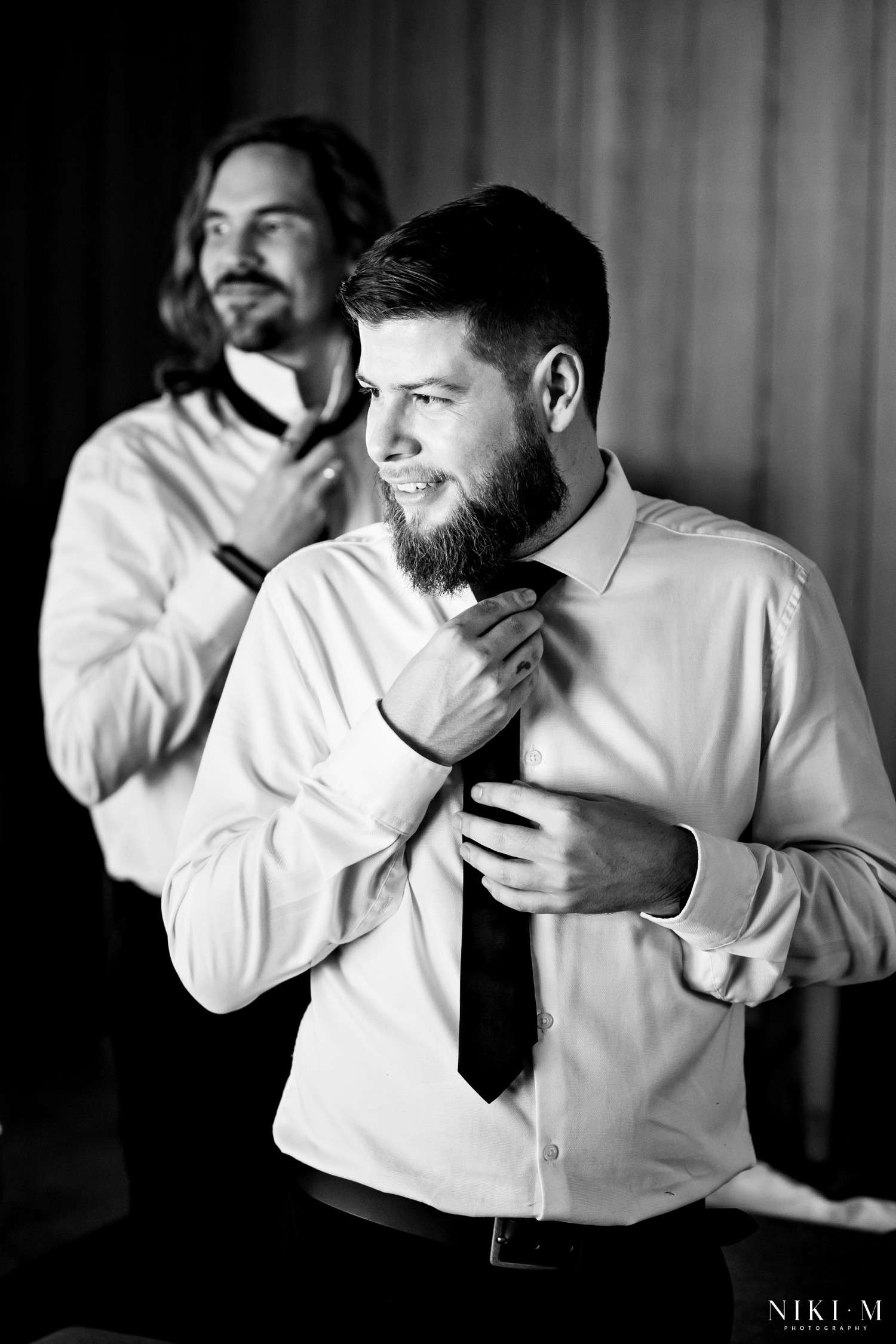 Groomsmen adjusting ties before a Drakensberg wedding ceremony, black and white