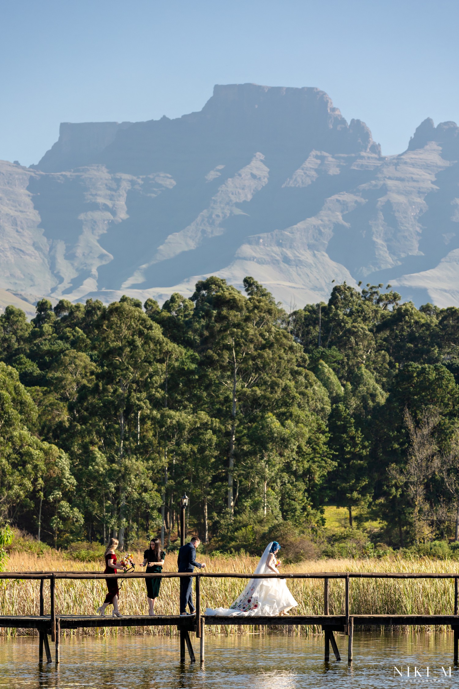 Bride in hand-embroidered veil on a jetty with the Central Drakensberg mountains behind her, Champagne Valley wedding