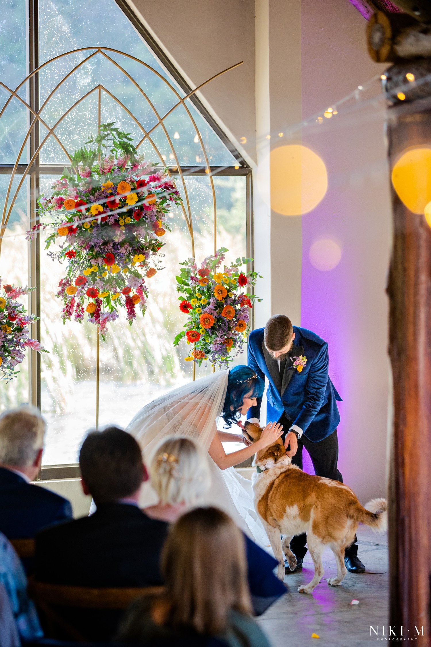 Bride and groom greeting dog Sadie at the floral altar at a Champagne Valley wedding ceremony