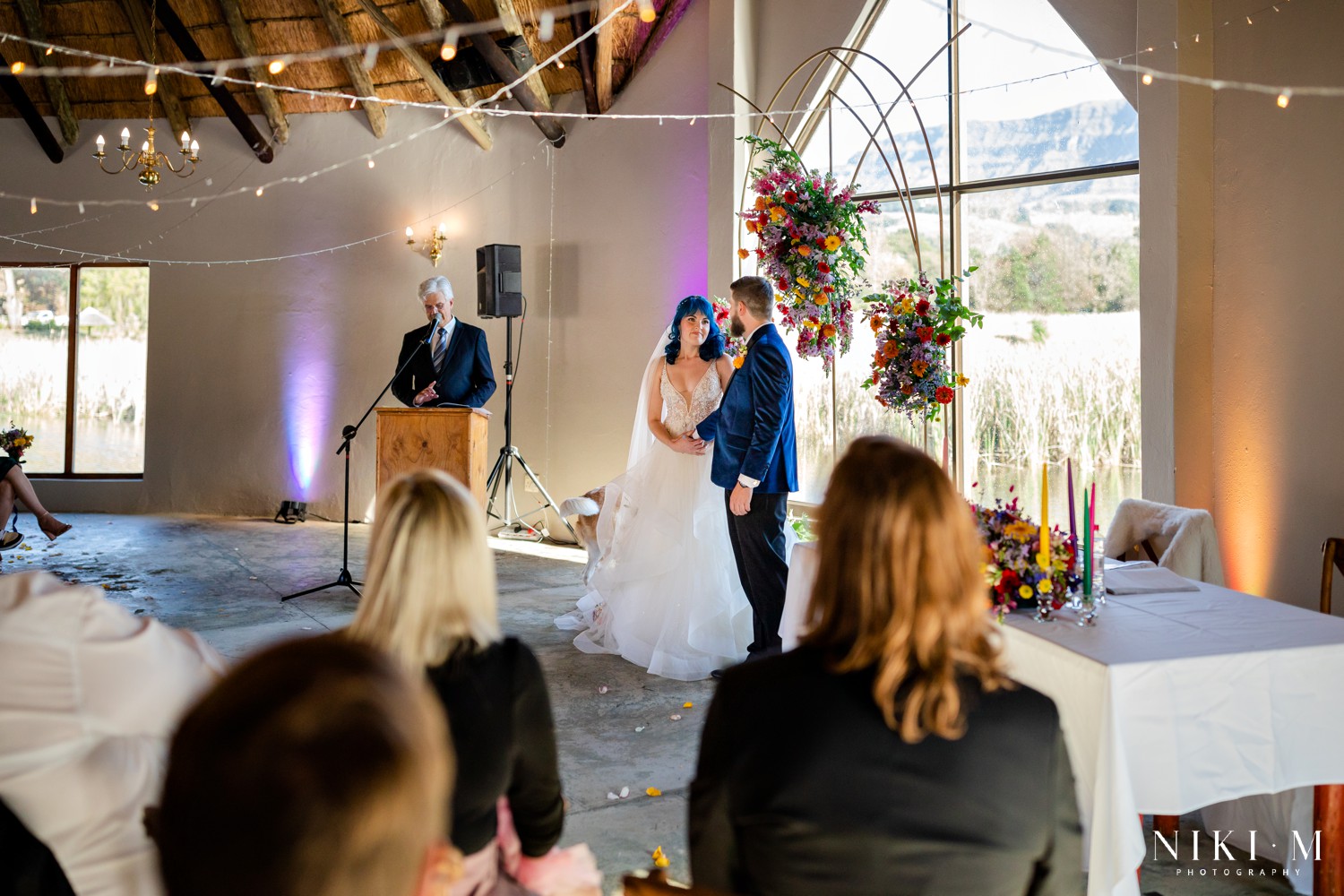 Wedding ceremony with the Drakensberg mountains through an arched window and colourful taper candles, Champagne Valley