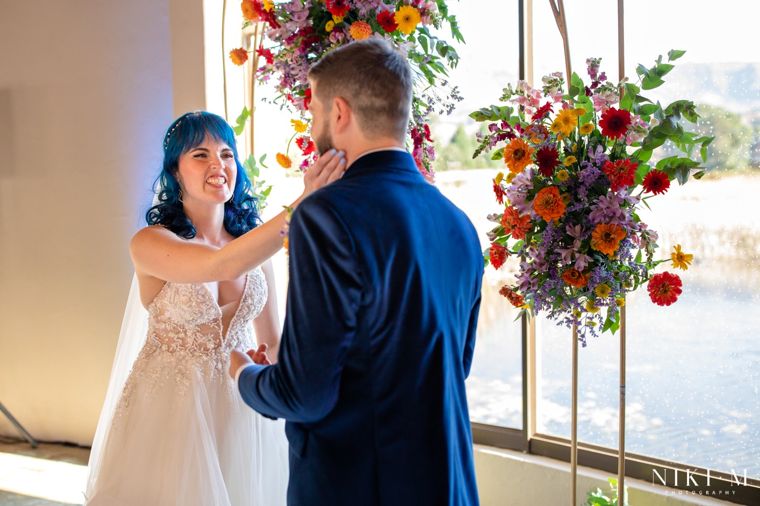 Bride cupping her groom's face at the altar beneath the wildflower arch at a Champagne Valley wedding