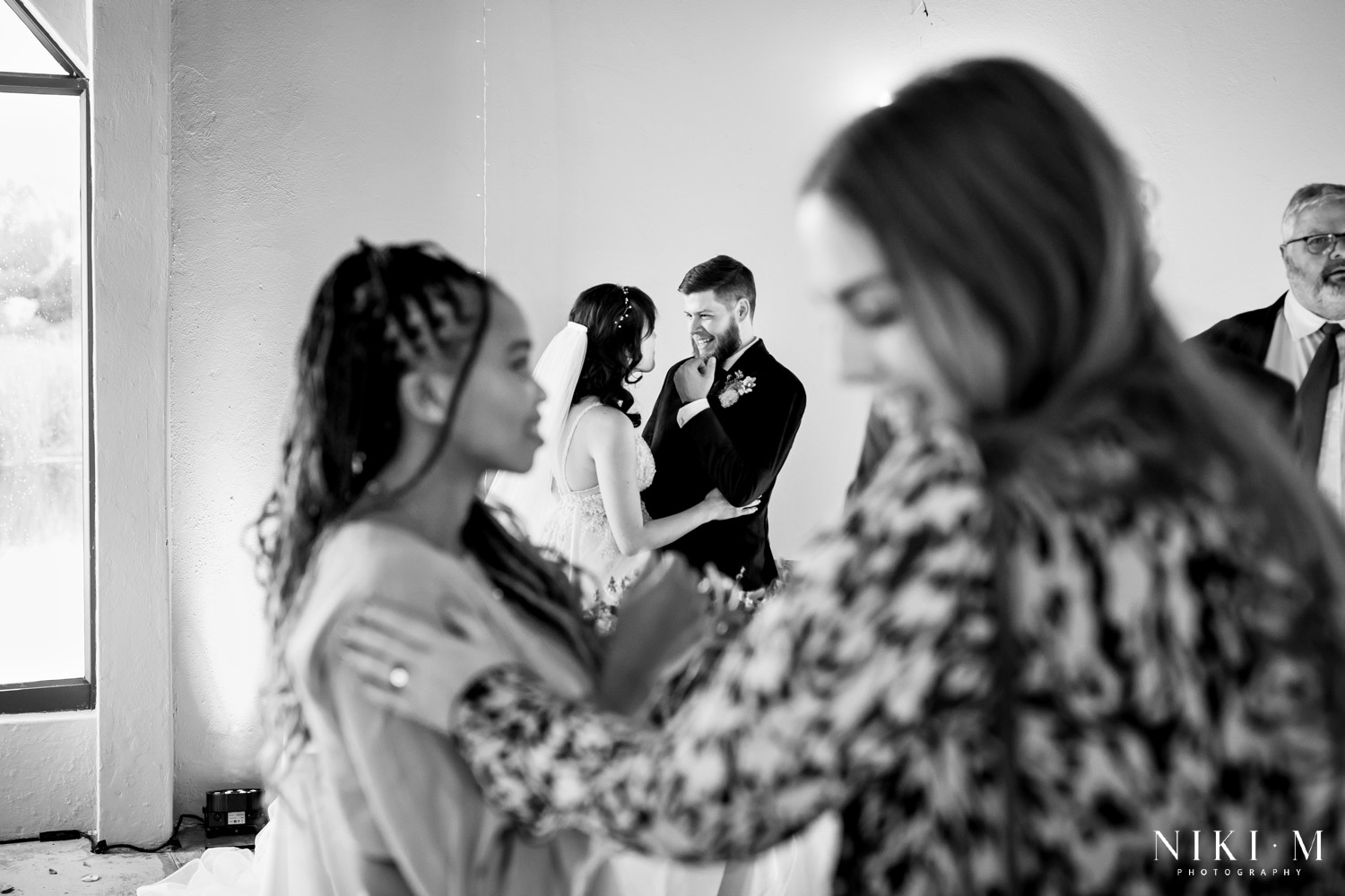 Black and white candid of newlyweds in the foreground with guests celebrating behind them, Champagne Valley wedding