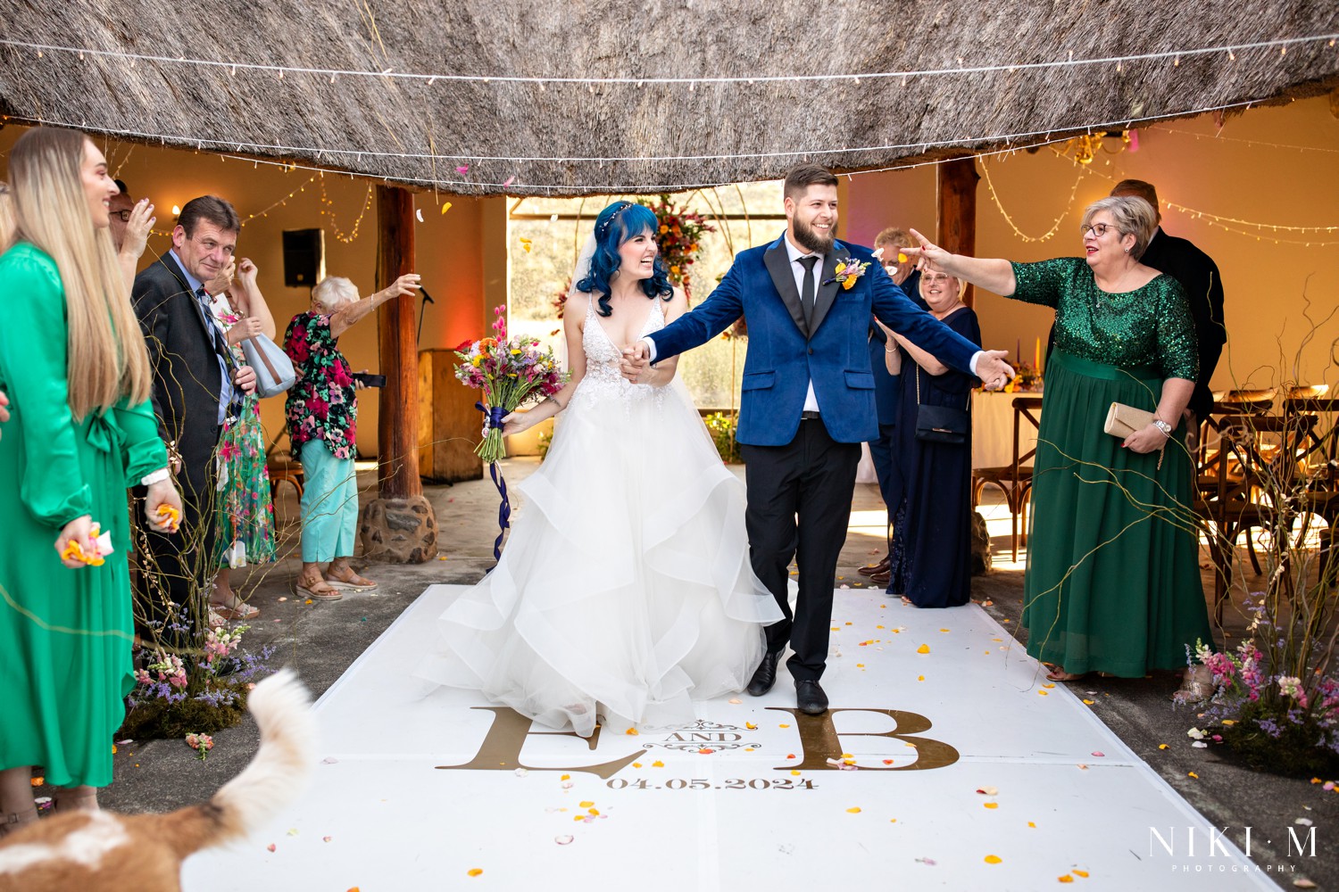Bride and groom walking the recessional with dog Sadie visible in the frame at a Drakensberg wedding
