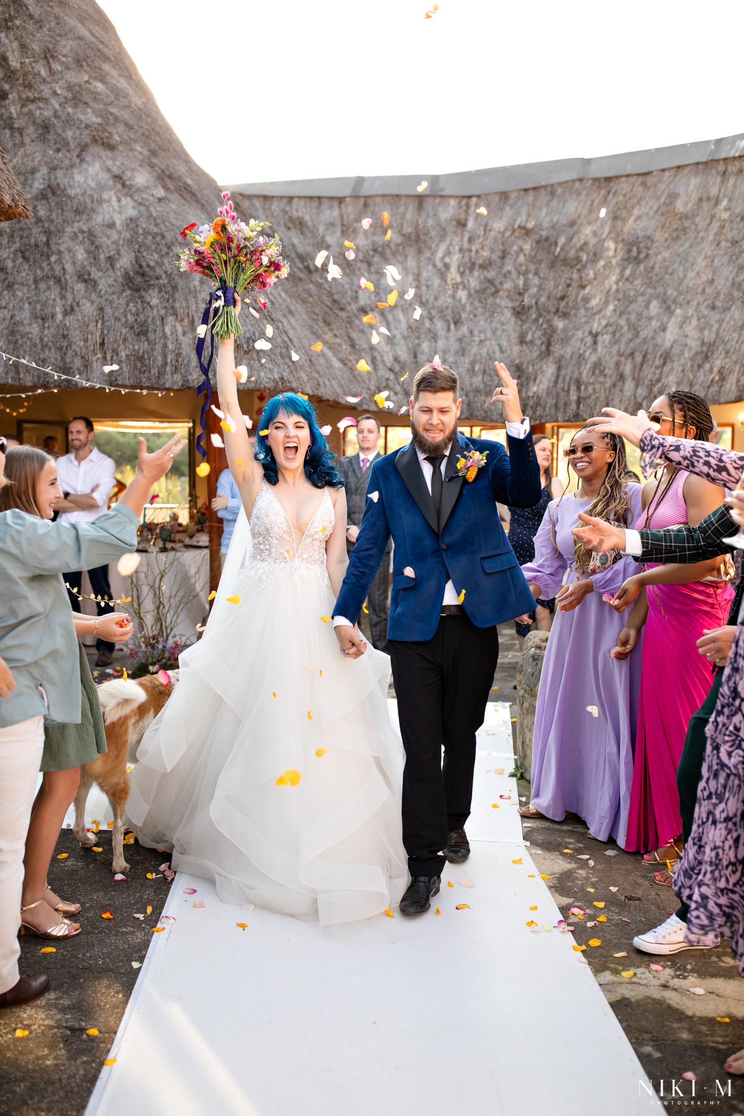 Bride raising her bouquet as confetti falls during the recessional at a Champagne Valley wedding