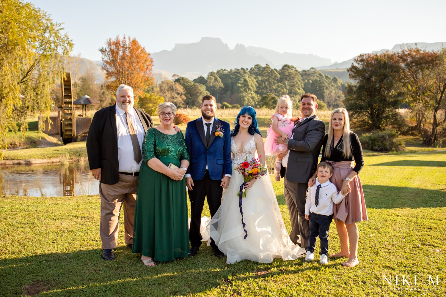 Family portrait with bride and groom, autumn trees and the Drakensberg escarpment at a Champagne Valley wedding