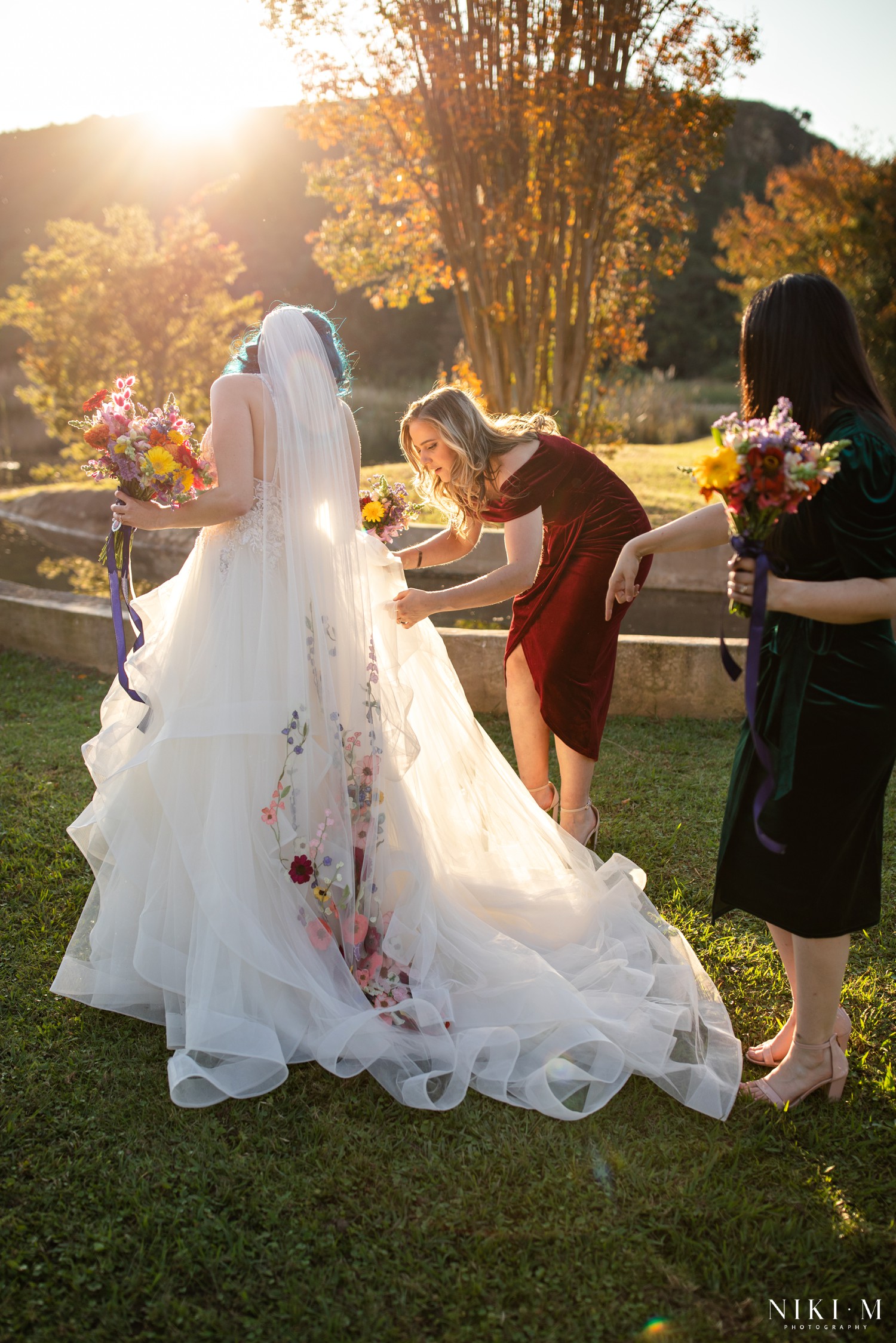 Bridesmaids arranging the bride's embroidered veil train at golden hour with the Drakensberg mountains behind them