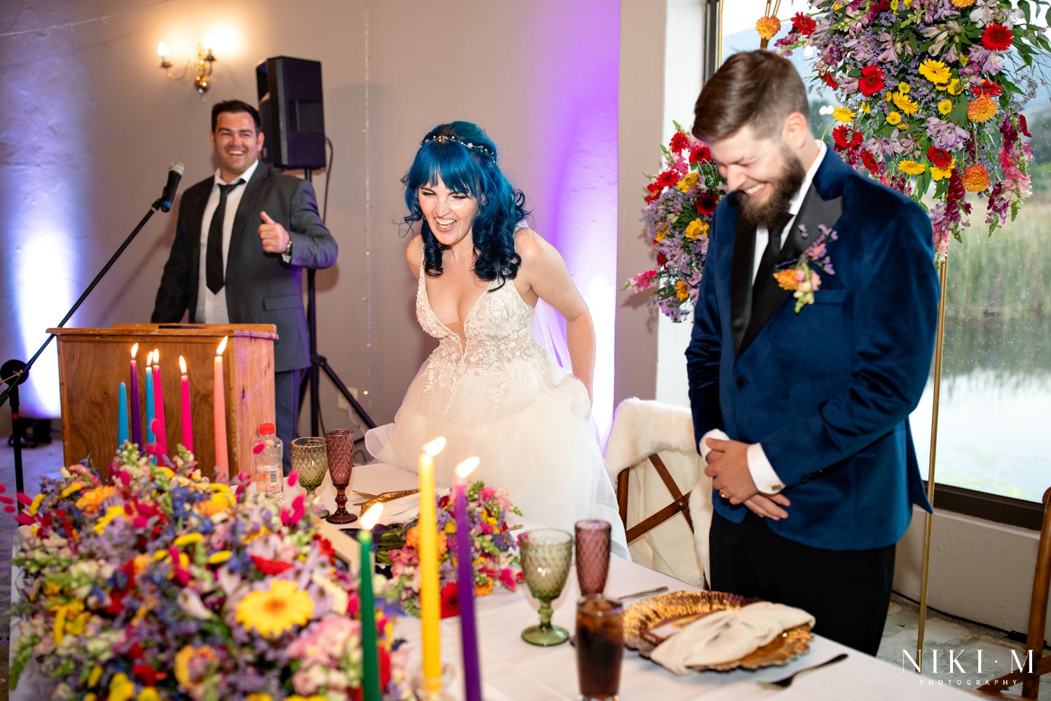 Bride being seated at her wedding reception surrounded by colourful candles and a hanging wildflower installation at a Drakensberg wedding