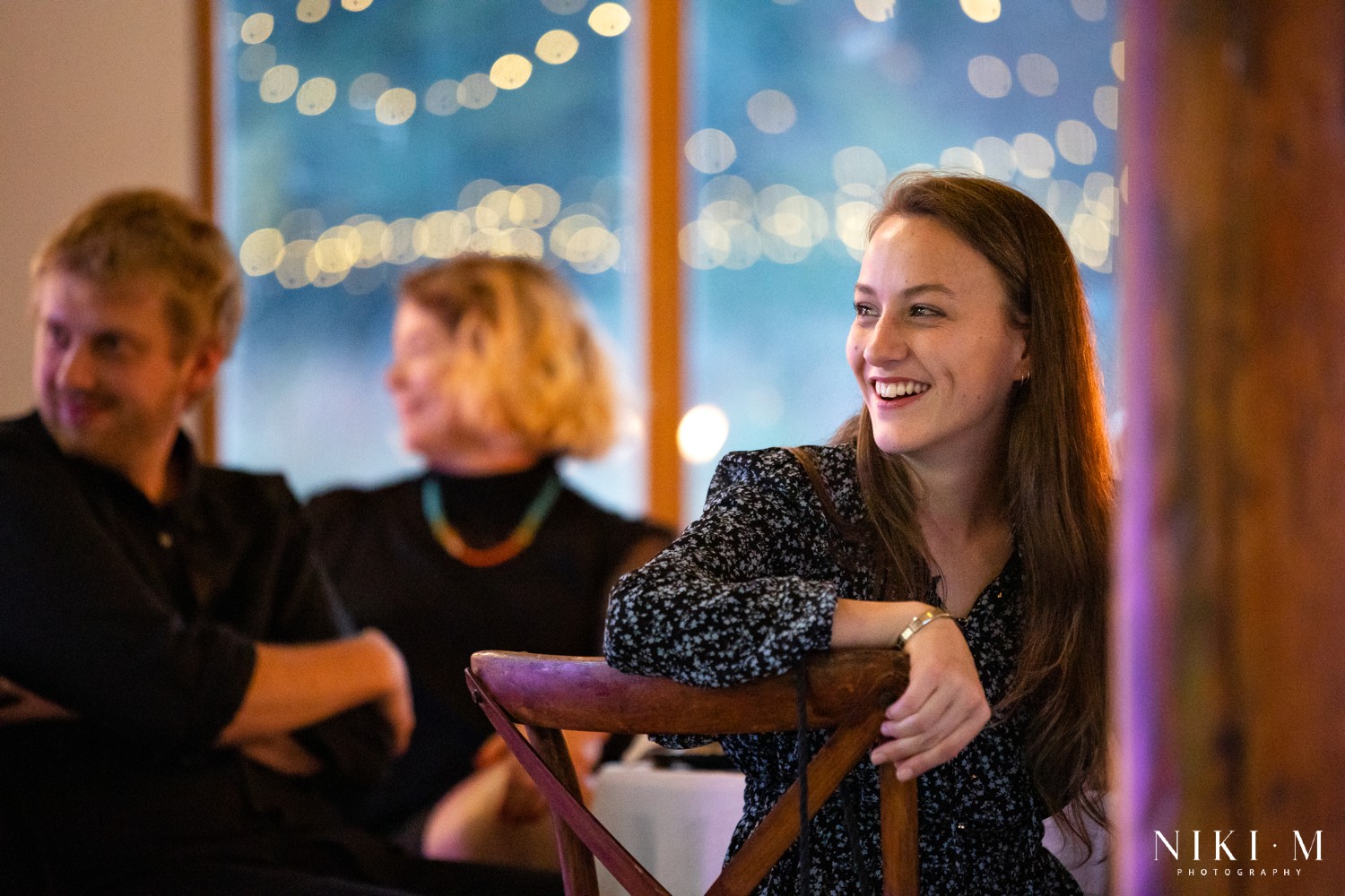 Wedding guest laughing during speeches with fairy lights bokeh behind her at a Champagne Valley wedding