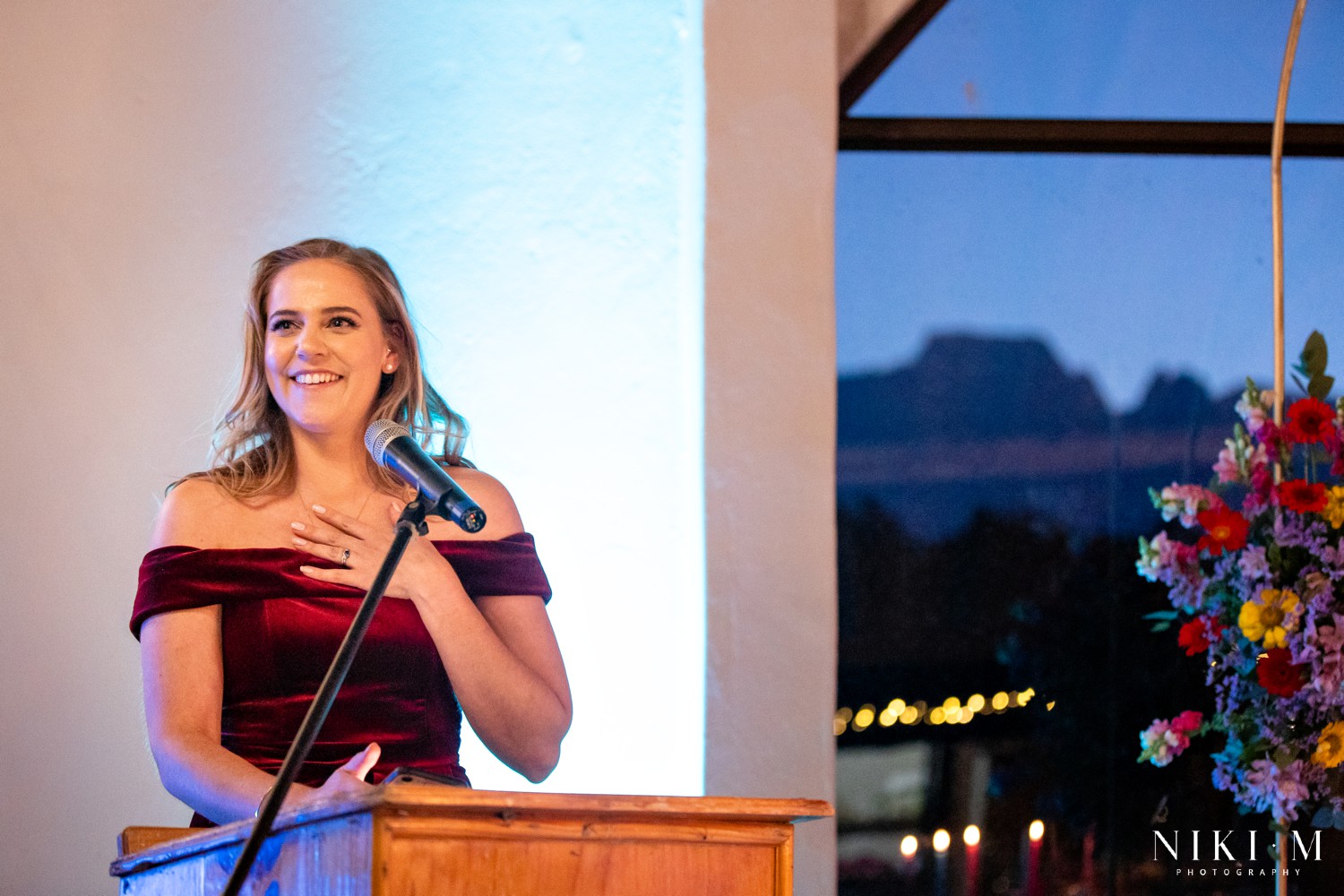 Bridesmaid giving her speech at the podium with the Drakensberg mountains visible through the window at dusk, Champagne Valley wedding